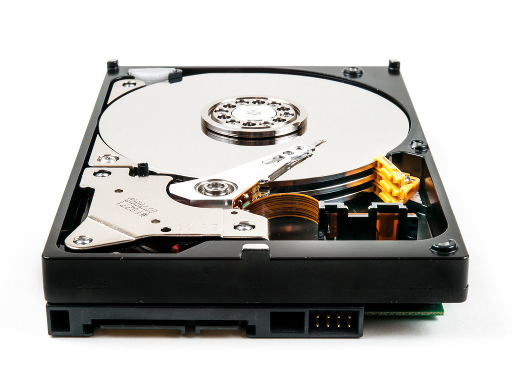 An opened hard disk drive with a reflective circular platter and read/write arm.
