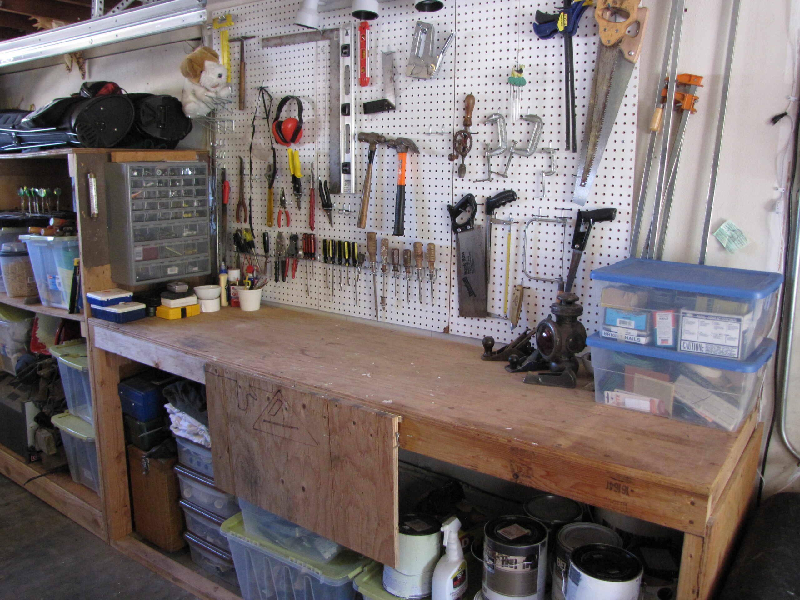 A workshop workbench with tools arranged above and around the working surface.