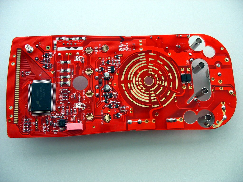 Front of a disassembled UNI-T UT61D multimeter circuit board with chips, contacts and wiring visible